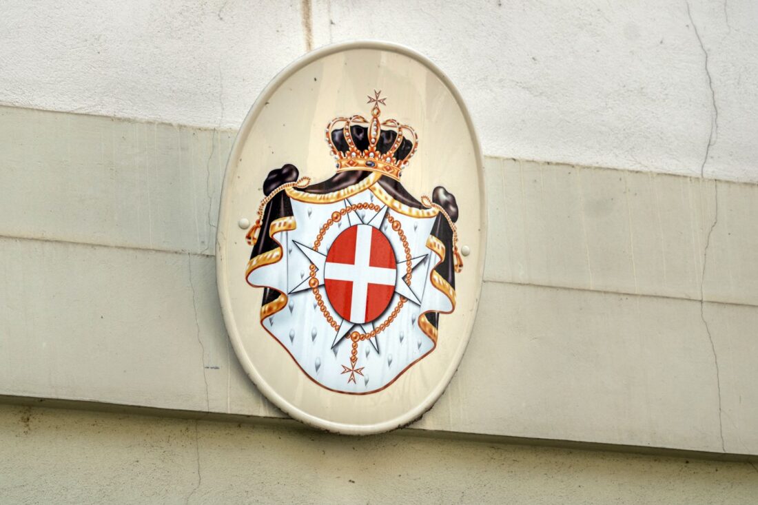 Coat of arms of the Sovereign Military Order of Malta mounted on a stone wall