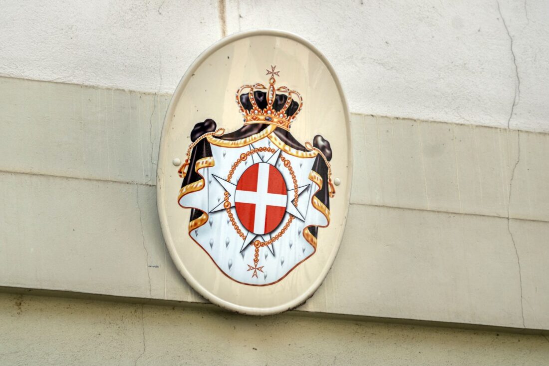 Coat of arms of the Sovereign Military Order of Malta mounted on a stone wall